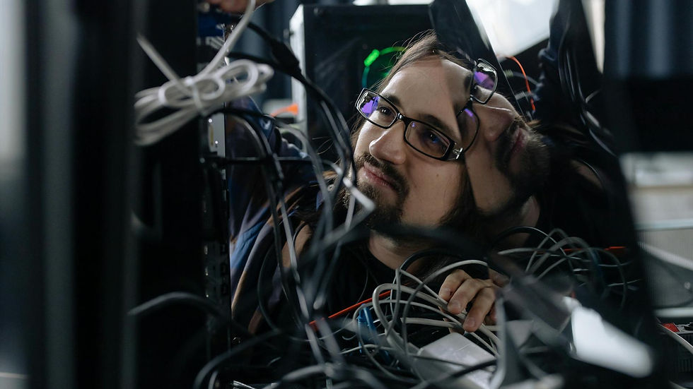 A skilled IT technician organizing tangled cables at his workstation in an office environment.