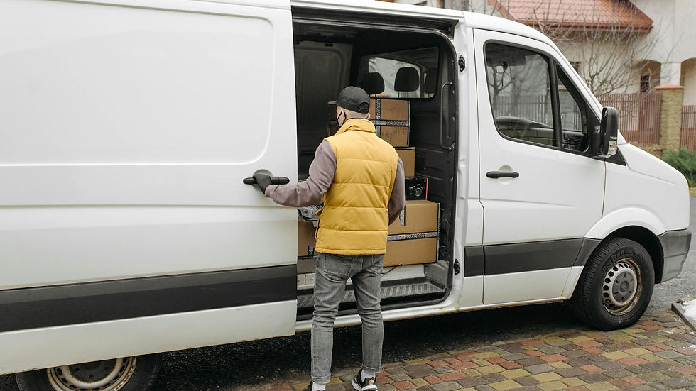 A delivery driver loads packages into a white van on a residential street.