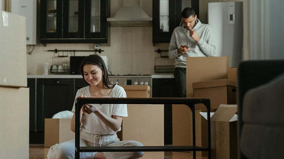 A young couple unpacking boxes in their new apartment kitchen, settling into a cozy home.