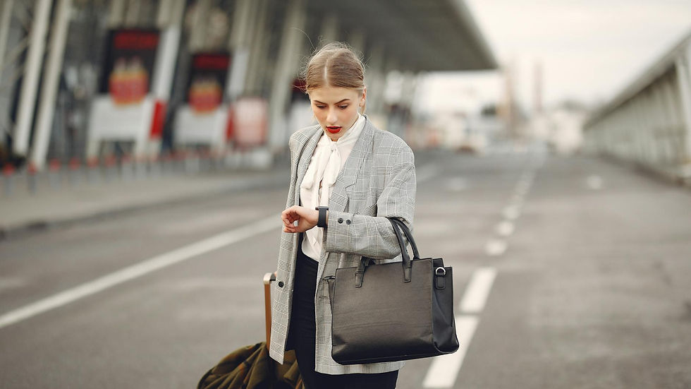 A businesswoman checks her watch while waiting at an airport terminal, looking concerned.