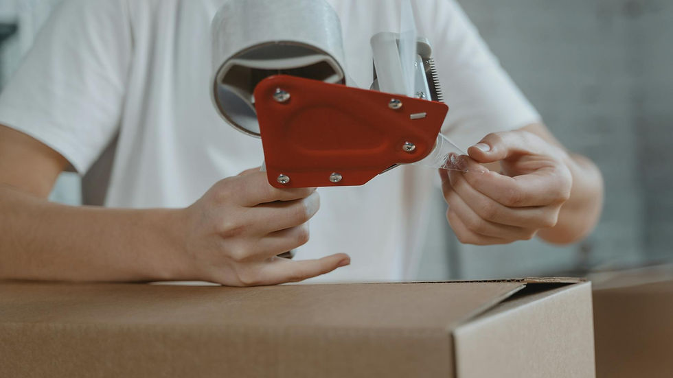 Close-up of person sealing a cardboard box with tape for packaging and shipping.