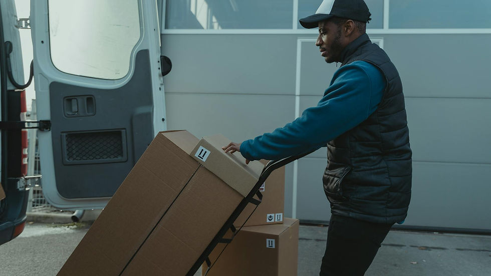 A courier delivers cardboard boxes using a trolley outdoors.