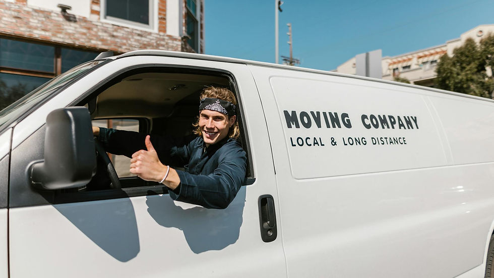 Smiling mover giving thumbs up from a moving company van parked outside.