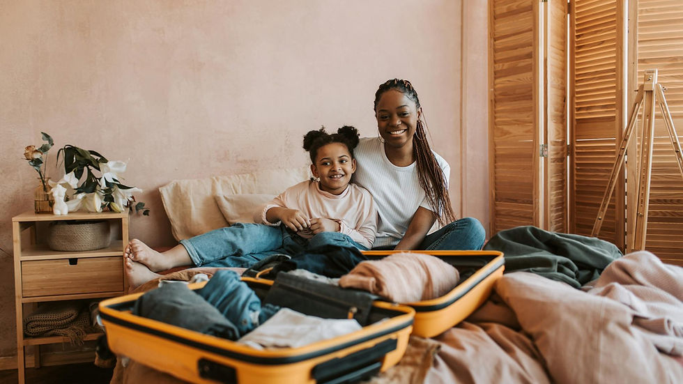 Smiling mother and daughter packing luggage together in cozy room.
