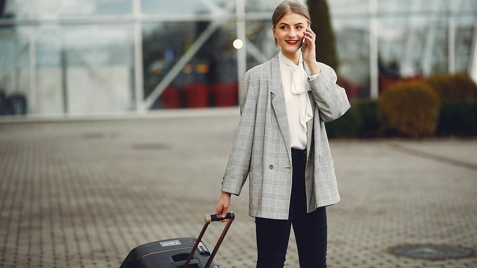 Confident businesswoman walking with luggage while talking on phone at airport terminal.