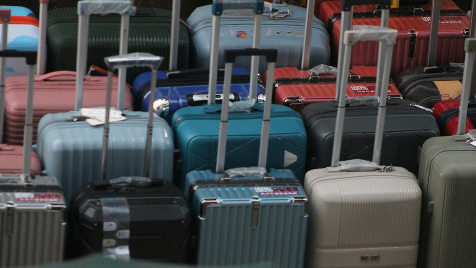 A variety of colorful suitcases with handles extended, ready for travel.