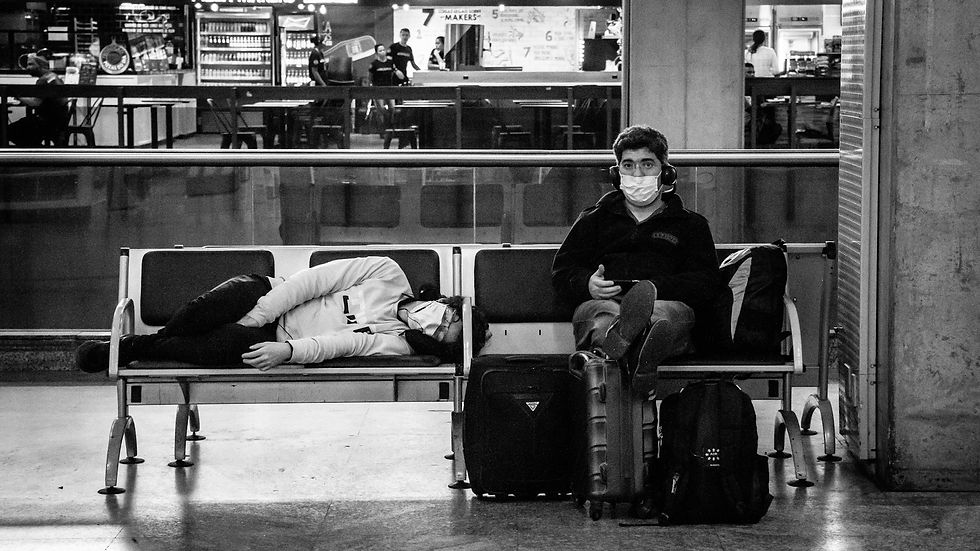 Two people resting in an airport, capturing the pandemic's impact on travel.