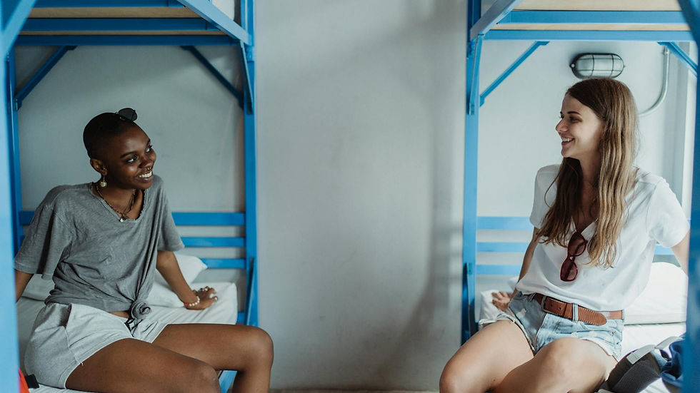 Two women enjoy a relaxed moment in a modern hostel bunk bed setting.