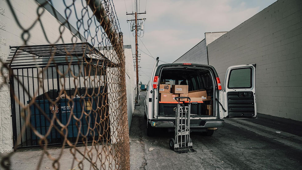 An open van loaded with boxes in an alley, ready for donation deliveries.