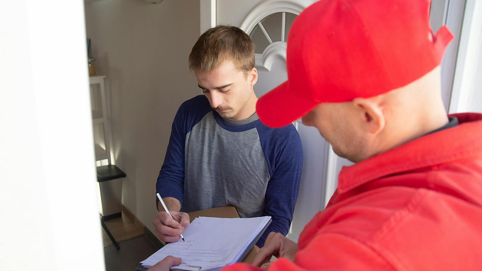 A delivery man in red uniform assists a young man signing for a package at the doorstep.