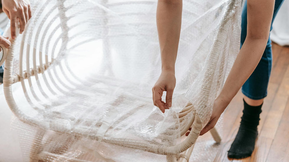 Close-up of a person wrapping a wooden chair in bubble wrap, preparing for moving or storage.