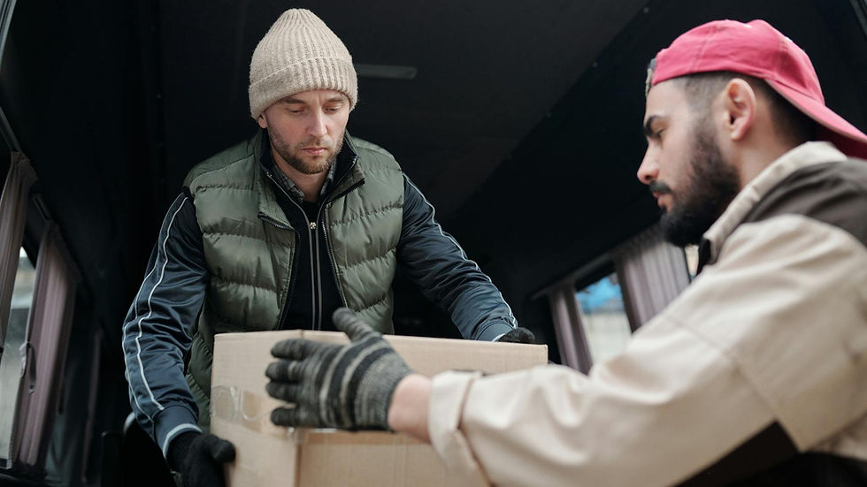 Two men unloading a cardboard box from a delivery van, showcasing teamwork.