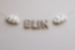 Thumbnail: Een handgemaakte slinger van wolvilt met de letters ELIN en zowel links als rechts 2 witte wolken met kleine hartjes