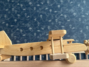 Een sfeervolle houten speelgoedvliegtuig als decoratie in een babykamer met een avontuurlijk reisthema.