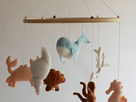 Babymobiel met vilten zeedieren zoals walvis, krab en zeepaardje, hangend aan een houten ring.