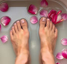 one pair of human feet soaking in a small tub of water with rose petals floating in the water.jpg