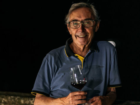 uomo di notte con calice di vino appoggiato a parapetto