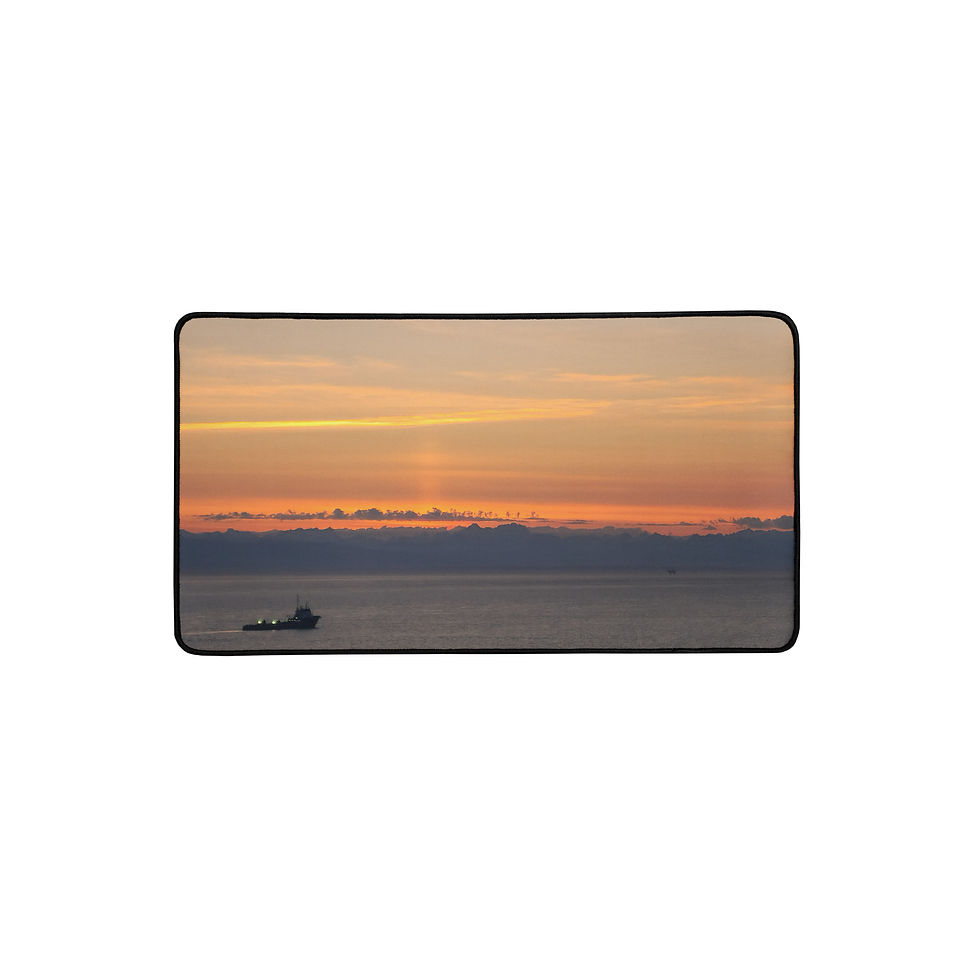 Alaska coastal sunset photograph printed across a gaming and work desk pad