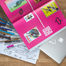 Caderno aberto com design criativo em fundo rosa sobre uma mesa com lápis, anotações e notebook, representando construção de reputação.