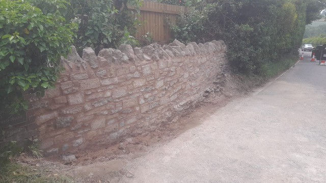 garden stone wall repaired after being hit by a car