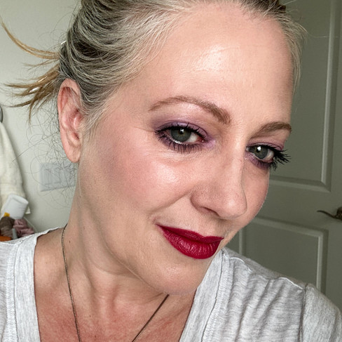 author with hair up in a bun with lavender eyeshadow and 721 Mythic fushcia on lipss