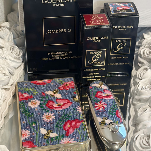 eyeshadow palette and rouge g lipstick in floral denim collection with boxes on a mirrored tray with rose trim