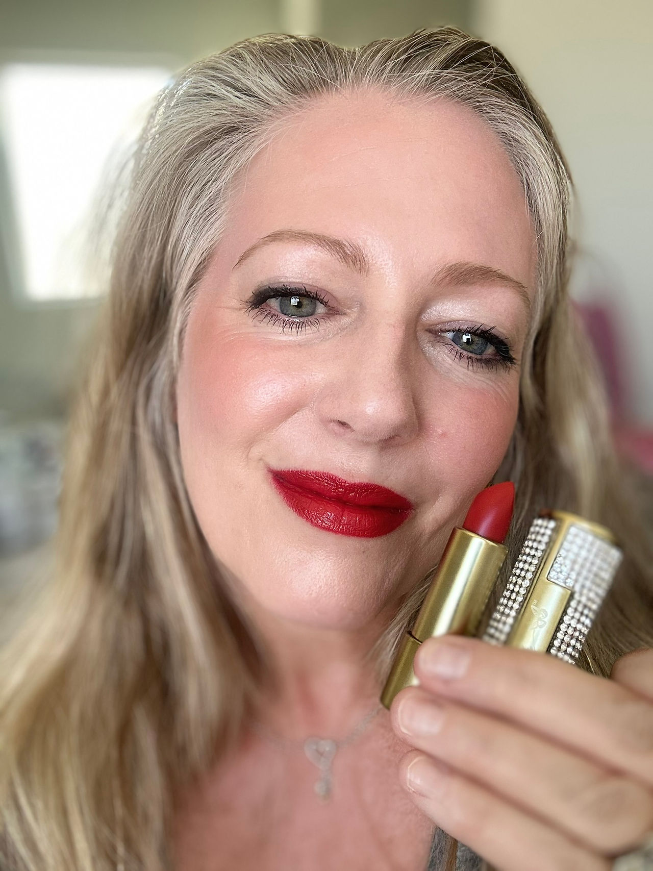 author wearing Jolene Red holding the lipsticks