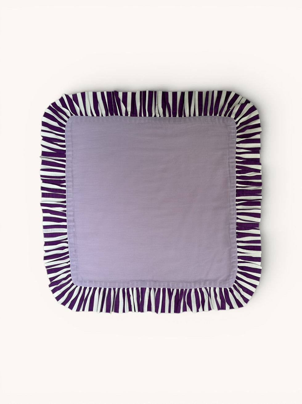 Pastel lavender cotton ruffle napkins with contrasting violet striped trim, styled on a dining table.