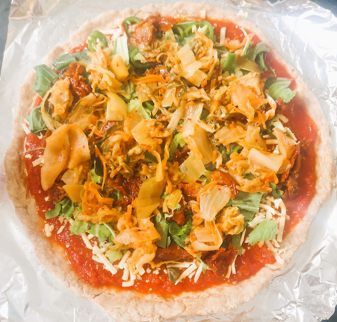 Homemade Pizza, topped with cauliflower leaves, sundried tomatoes, capers and Crafty Kimchi