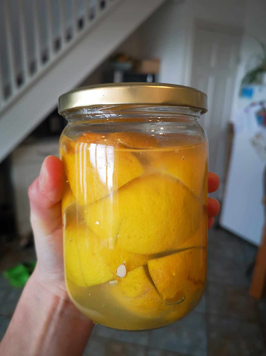 Fermented lemons in jar held by hand