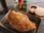 Seasoned turkey breast on a rack with garlic powder, Old Bay, oregano, and salt. Black pepper grinder to the side on checkered cloth.