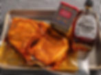Packaged marinated meat, a can of smoked paprika, and a bottle of organic maple syrup on a tray. Background features a checkered pattern.