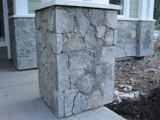 Natural stone veneer support post at a home's covered entryway, hand-fitted in a random fieldstone pattern