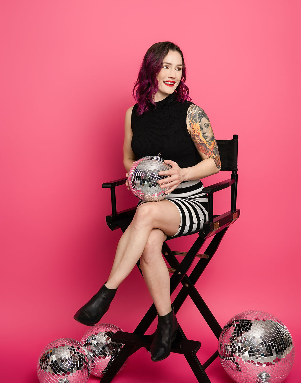 A photo of Amanda Goodfellow, owner of Digital Unicorn, sitting in a directors chair with a disco ball in her hands.