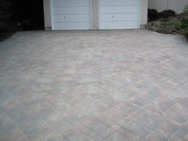 Finished concrete paver driveway in a diamond lattice pattern installed by Victoria Landscaping Ltd leading to a home's double garage.