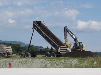 dump truck and excavator working on a flat job site in victoria bc