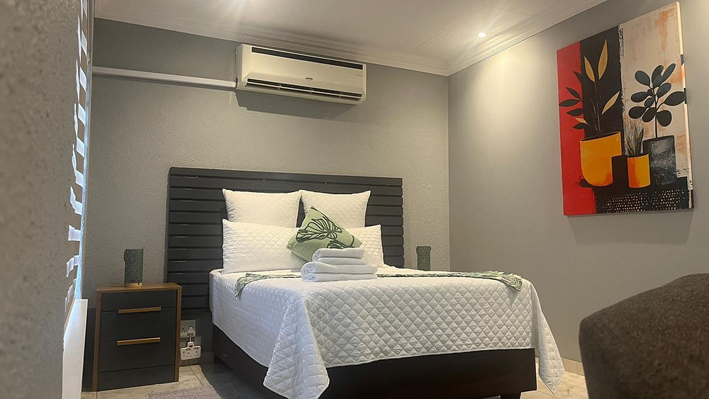 Modern bedroom with a white bed, green throw, and wall art