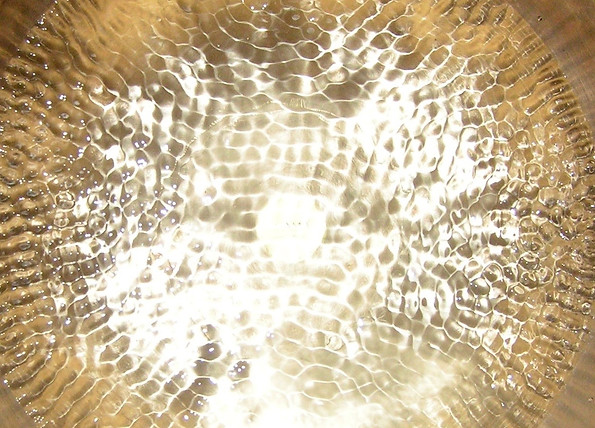 Wasserklangbild in einer goldfarbenen Beckenklangschale für die besondere Wirkung von Sound Healing Meditationen mit Klangschalen auf unseren Körper