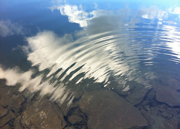 Wolken, die sich im gewellten Wasser eines Sees spiegeln für die heilende Wirkung von Naturaufnahmen