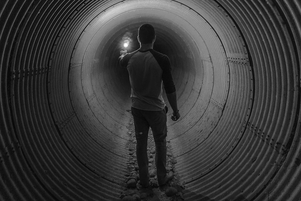 Man standing in dark tunnel with flare in his hand