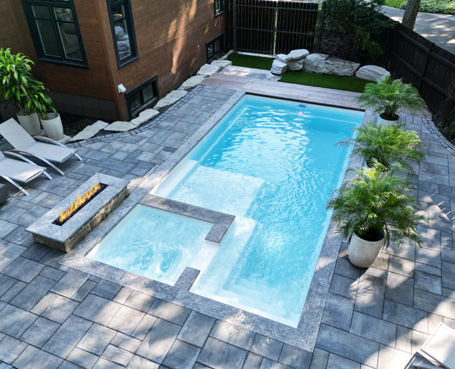 Une piscine en fibre de verre entièrement installée avec un beau pavé uni