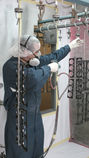 An image of a person in protective gear applying spray coating to a customer part.
