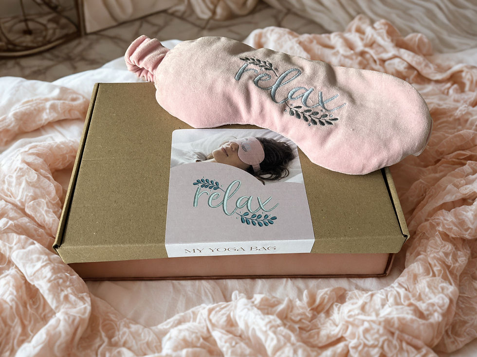 Blush pink organic lavender and flax seed eye mask with Relax embroidery, displayed on a kraft gift box wrapped in tissue pap