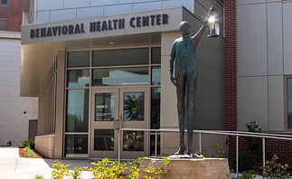 sculpture of long leg man holding light lamp