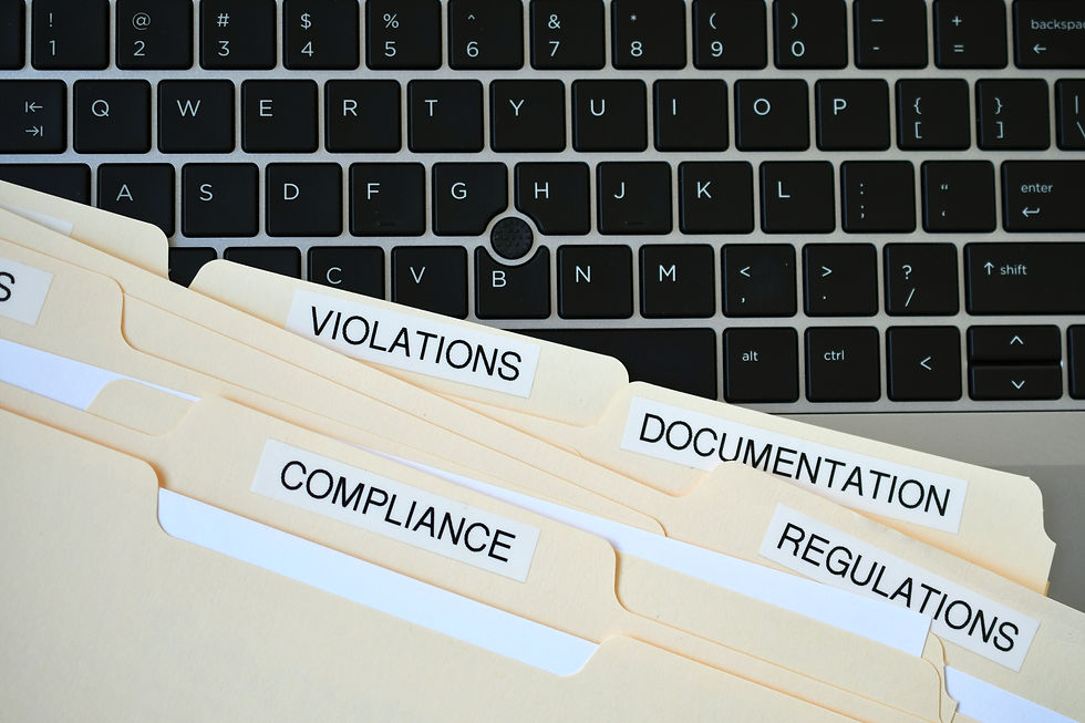 Czarna klawiatura laptopa i teczki z etykietami VIOLATIONS, COMPLIANCE, DOCUMENTATION, REGULATIONS.