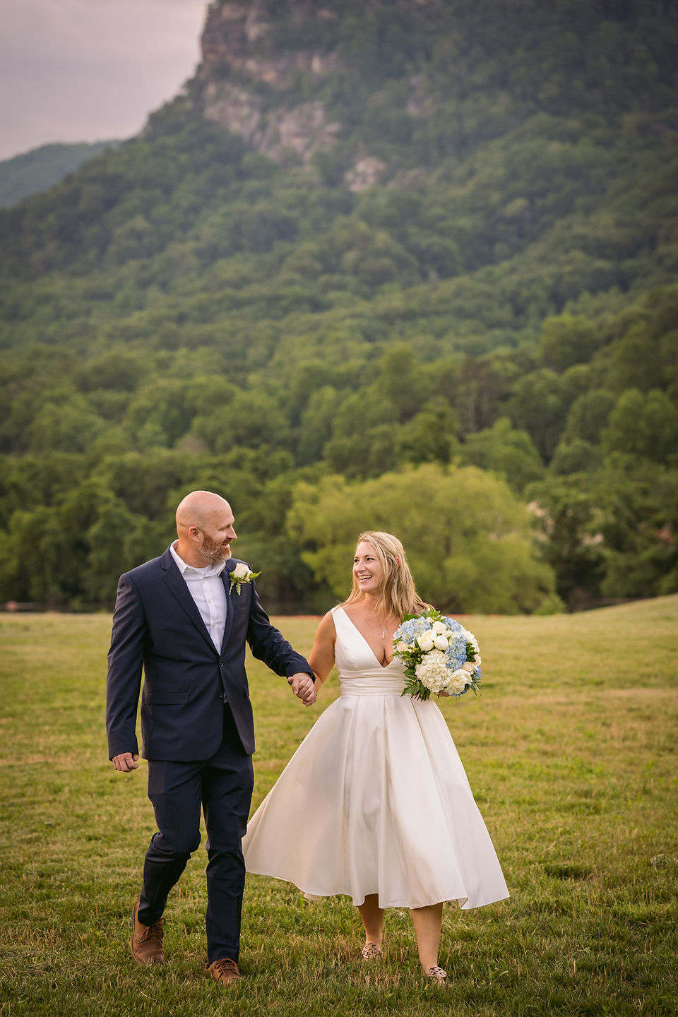 bride and groom holding hands in a field