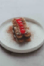 Completed black forest tiramisu with cacao powder sprinkled ontop presented on a round white plate.