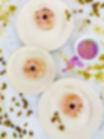 Three doughnuts seen from overhead with pink icing and green shelled pistachios