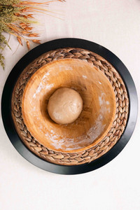 Ball of mixed dough in a large wooden mixing bowl.