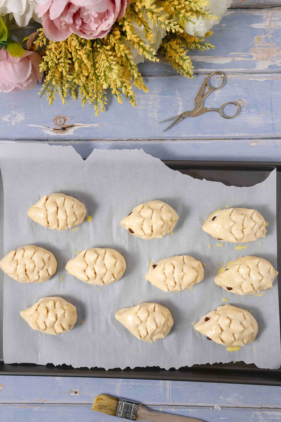 Little hedgehog shaped bread buns on a baking sheet before baking.